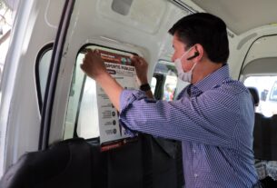 Alfredo Vinalay adhiere un cartel en una unidad de transporte de pasajeros en San Bartolo, Naucalpan